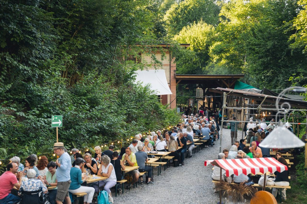 Theaterbeiz im Steinbruch · lange Tische, Lichterketten, Sommerabend